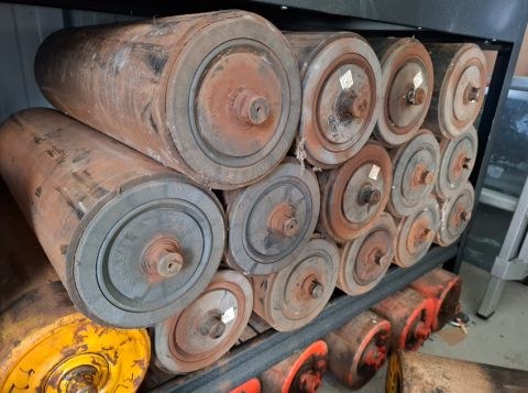 A shelf stacked with rusted end-of-life conveyor rollers
